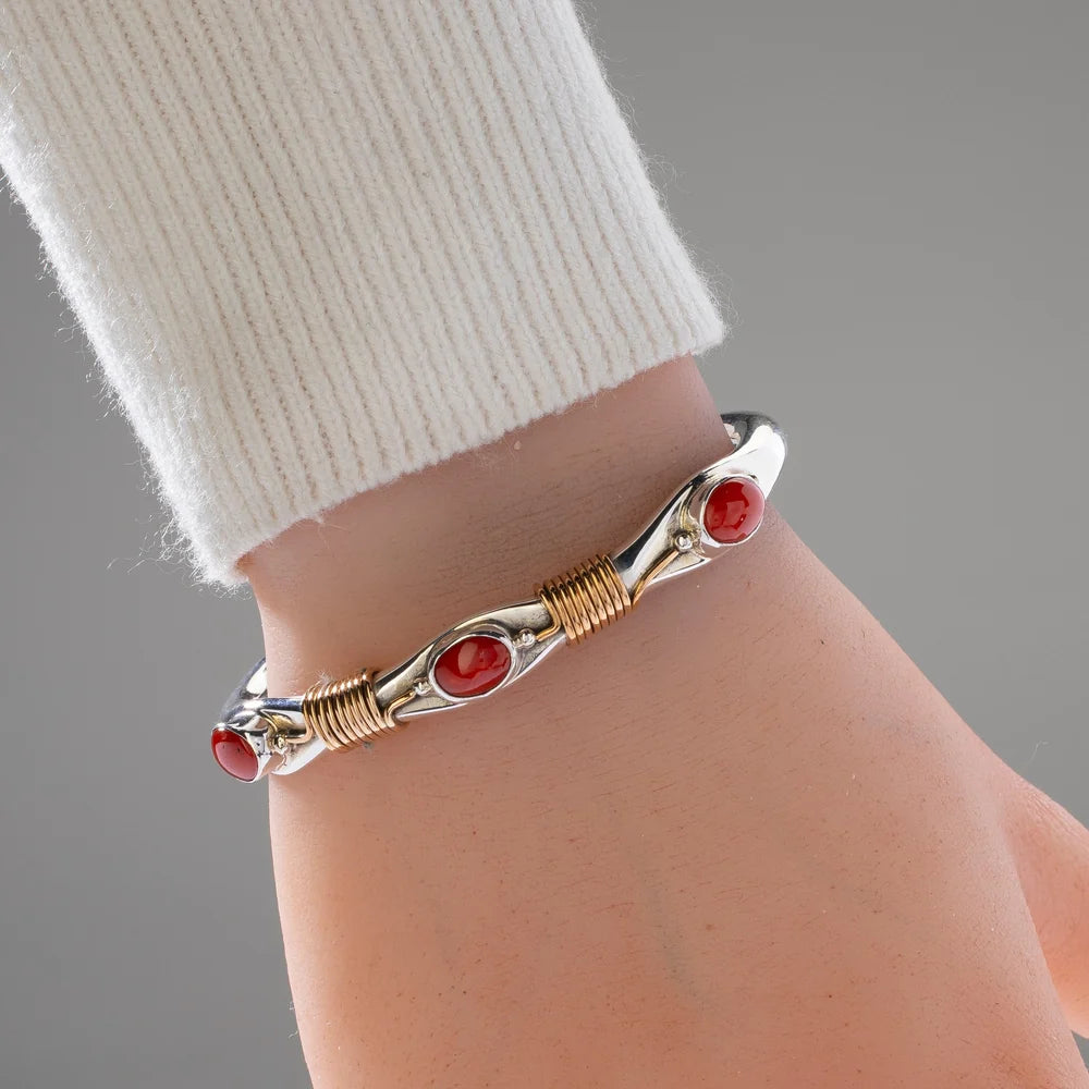 Russell Sam Navajo sterling silver and 12K gold-filled cuff with red coral worn on wrist
